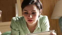 young woman lying on motel bed reads from tablet computer Stock Footage