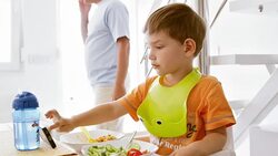 Boy eating and watching video while father talks on phone Stock Footage