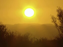 WS View of Sun setting behind hazy orange hued mountains / Namaqualand, Northern Cape, South Africa Stock Footage