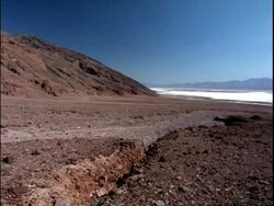 WA dry landscape, mountains and blue sky in background, Death Valley National Park, California, USA Stock Footage