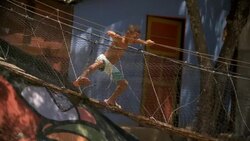 Young Brazilian boy jumps up and walks across swinging rope bridge Stock Footage