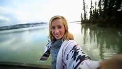 Young woman standing on wooden pier takes selfie portrait Stock Footage