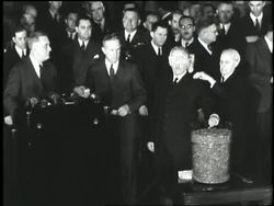 President Franklin D. Roosevelt reads a serial number drawn by United States Secretary of War Henry L. Stimson for the draft lottery during World War II. News Clip