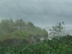 Man walking on lake side bank hit by storm waves and spray, Philippines, Typhoon Mirinae 2009 Stock Footage