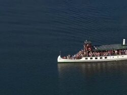 Aerial view zoom out of tourists riding on an old steamer on Windermere in the Lake District / lake dotted with other boats / Cumbria, England Stock Footage