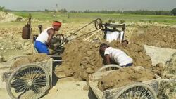 Men in Bangladesh dig soil and clay mixed with water which is churned by machine in preparation of brick making  Stock Footage