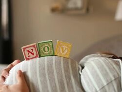 A pregnant women using blocks to spell the month of NOV on her stomach. Stock Footage