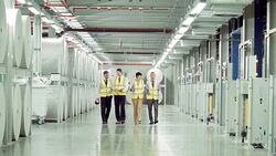 Workers walking past large paper spools in paper mill Stock Footage