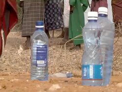 Bottles of water and people walking by them Stock Footage