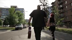 Cool young couple with guitar walking down sunny urban street Stock Footage