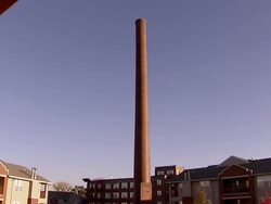 WS TD  Tall brick smokestack surrounded by houses is demolished using explosives and collapses / Villa Park, Illinois, USA Stock Footage