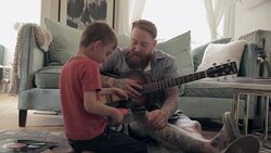 Father and son with guitar listening to records on living room floor Stock Footage