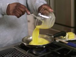 MS TD TU Dad pouring scrambled eggs into skillet / Dallas, Texas, USA Stock Footage