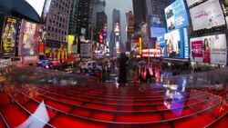 Pedestrians pass by red bleachers set up in the middle of Times Square. Stock Footage