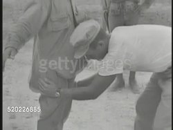 1945: OKINAWA, JAPAN: POW CAMP: 'No Admittance' sign by guard tower. US Marine 'patting down' Japanese soldier prisoner. PAN Japanes POWs standing outside. Pacific Theater, WWII, World War II. Instructional Video