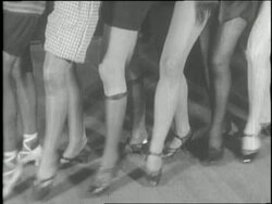 A group of showgirls practice a routine with a choreographer. News Clip