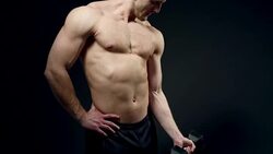 beautiful athlete trains with a dumbbell on a black background Stock Footage