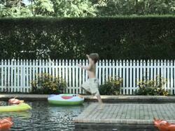 Boy running and jumping into swimming pool, slow motion Stock Footage