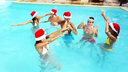 Happy people with Santa hats dancing in swimming pool. Stock Footage