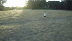 AERIAL PAN woman jogging around sharp turn in field Stock Footage