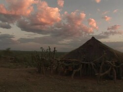 Long Shot static - Rosy clouds gather over a grass hut in Ethiopia / Ethiopia Stock Footage