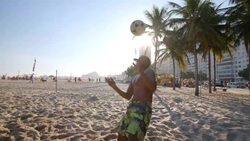 Brazilian player braces himself and heads soccer ball over net in beach footvolley match Stock Footage