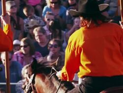 Spectators watch riders with flags and horses perform a routine at a rodeo - shot in slow motion. Stock Footage