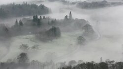 Looking down into the Langdale Valley above valley mist formed by a temperature inversion on Loughrigg, near Ambleside in the Lake District National Park, with cars driving on the Hawkshead road. Stock Footage
