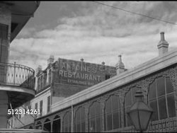 1952: NEW ORLEANS: FRENCH QUARTER: TU Angled XWS 'Antoine's Restaurant' sign painted on upper section of Rue Saint Louis building side wall, partial curved gallery (balcony), ornate ironwork around windows, lamp post top FG.    French-Creole, Iconic Instructional Video