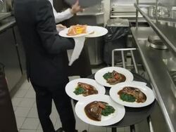 POV waiters taking prepared plates from the plating area in a restaurant kitchen to carry them to the dining room; camera follows waiter Stock Footage