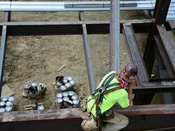 A steelworker grabs a swinging support beam at 12-story commercial construction site Stock Footage