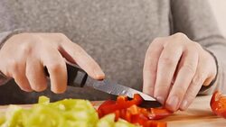 Woman slicing red bell pepper on cutting board, close up Stock Footage