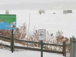 WS View of DNR signage, ice fishers and ice fishing houses at Medicine lake during winter / Minneapolis, Minnesota, USA Stock Footage