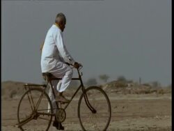 MS Pan right, Gujarat, Indian man cycling through desert, Gujarat, India Stock Footage