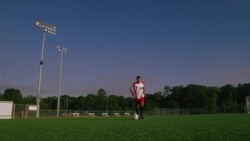 A soccer player dribbles a ball along a soccer field. Stock Footage