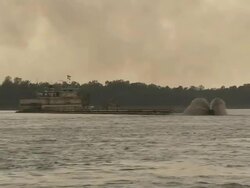 Long Shot hand-held - A dredger sprays water in the Mississippi River under a cloudy sky / Mississippi River Stock Footage