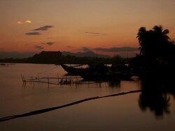 WS T/L View of Evening sky reddens and turns to night over river view with riverboats, moorings, building, trees all reflecting in river / Hoi An, Vietnam Stock Footage