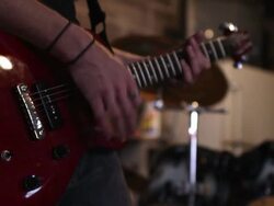 Panning view of man playing electric guitar with drummer in the background. Stock Footage