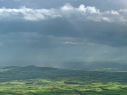 Aerial wide shot rain clouds and rainbow over green landscape / County Cork, Ireland Stock Footage