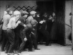 B/W 1917 policeman Charlie Chaplin jumping into air + kicking group of men in bar Stock Footage
