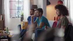 Guys sitting on couch watching horror movie Stock Footage