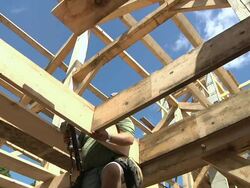 MS CS ZI Carpenter nailing wood plank in place while framing an energy efficient post / Grass Lake, Michigan, USA     Stock Footage