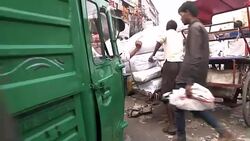 Tradesmen pushing laden down cart through bazaar in India News Clip