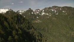 Snow dusts the summits of heavily wooded mountains. Stock Footage