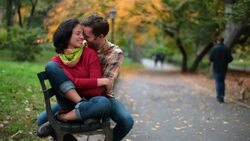 New York couple nuzzle on park-bench in Central Park as lamp-post flickers to life (dolly-shot) Stock Footage