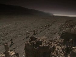 WS PAN Camel train in rocky valley salt flat / Republic of Djibouti Stock Footage