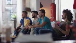 Guys sitting on couch watching funny movie Stock Footage