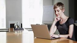 Businesswoman at conference table using laptop drinking water Stock Footage