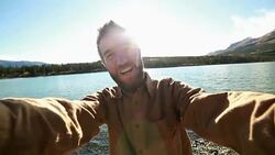 Young man taking selfie by Alpine lake Stock Footage