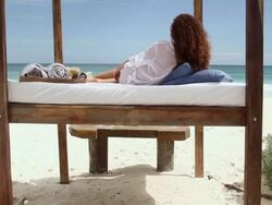 Woman lying on bed on sandy beach Stock Footage